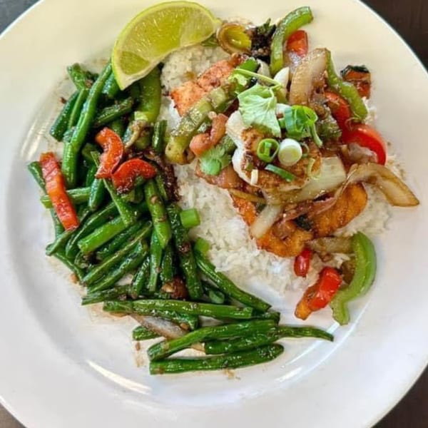 Yum Thai's chicken and green bean stir-fry with rice, bell peppers, onions, and a lime wedge.
