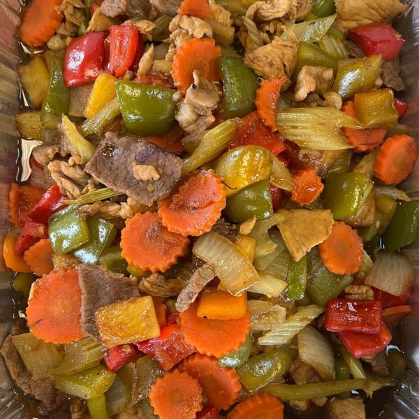 Close-up of colorful Thai stir-fry with beef, chicken, bell peppers, carrots, and celery.