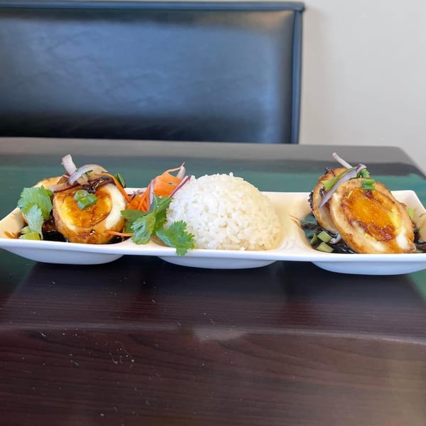 Yum Thai's fried eggs with sweet tamarind sauce, cilantro, and rice on a white plate.