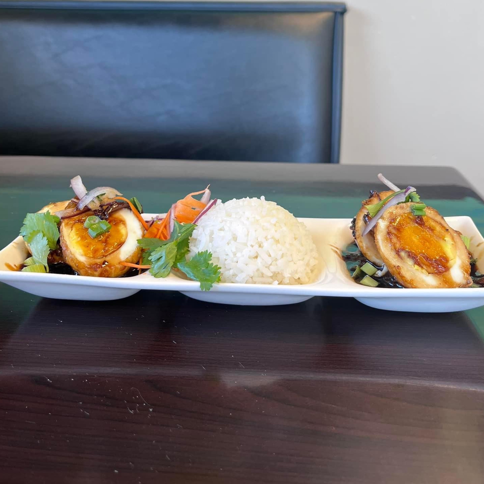 Yum Thai's fried eggs with sweet tamarind sauce, cilantro, and rice on a white plate.