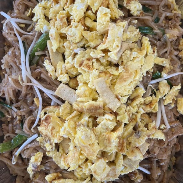 Close-up of Yum Thai's Pad See Ew with wide noodles, bean sprouts, green onions, and scrambled egg.